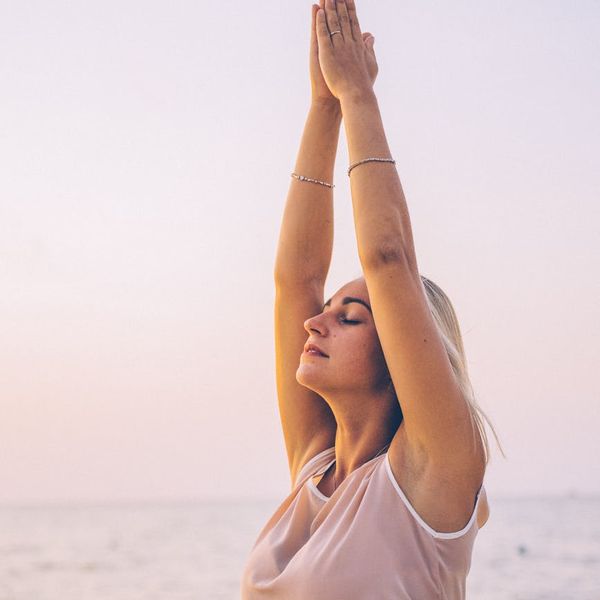 Person feeling energized and stretching outdoors at sunrise.